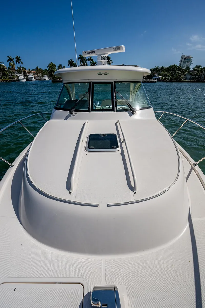 Slide: The Image of 2014 Pursuit 345os boat on water, clear sky, palm trees in background. - 18