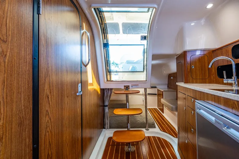Slide: The Image of Interior of 2014 Pursuit 345os boat with wood finishes and modern kitchen amenities. - 23