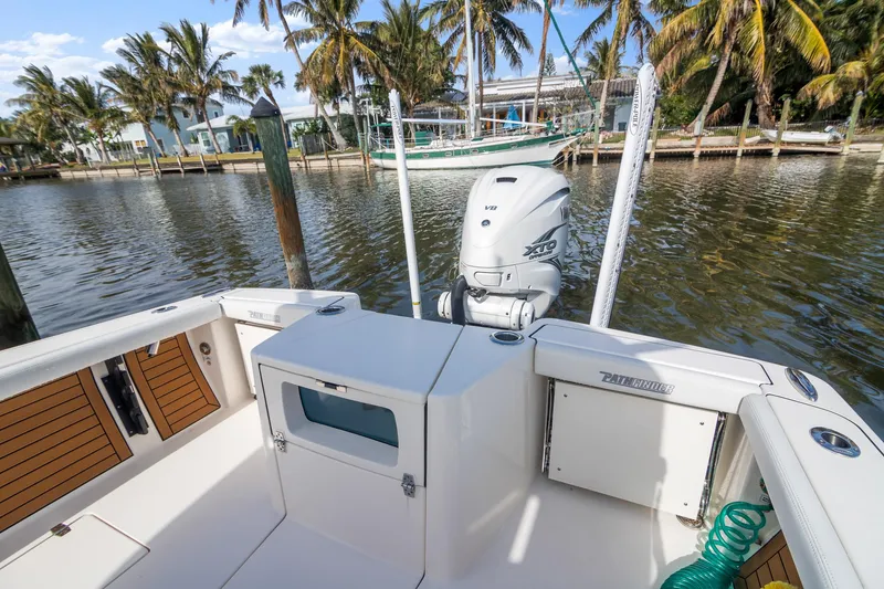 Slide: The Image of 2023 Pathfinder 2700 Open boat docked by palm trees, featuring a spacious deck and outboard motor. - 6