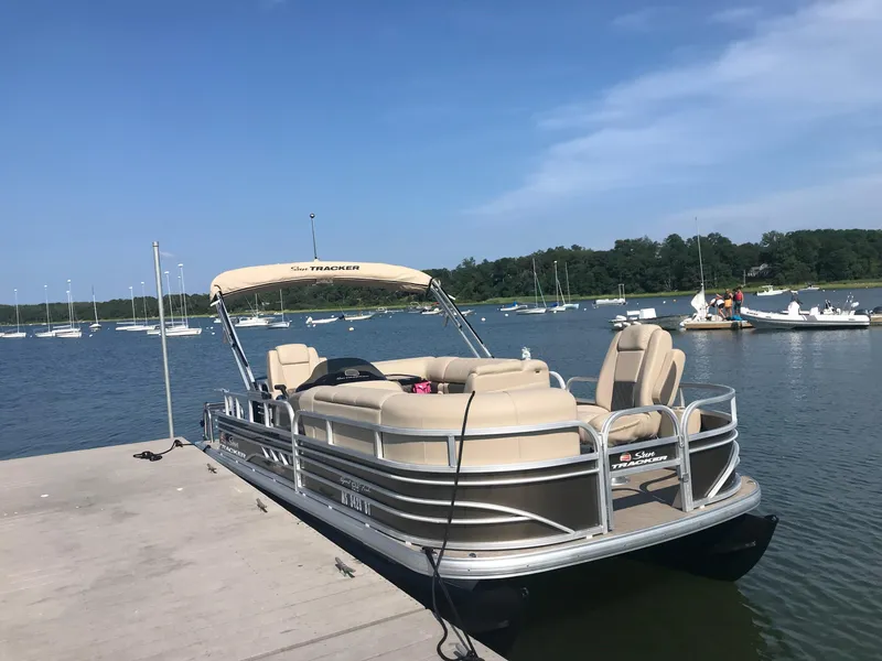 The Image of 2023 Sun Tracker SportFish 20 DLX pontoon boat docked on a sunny lake. - 0