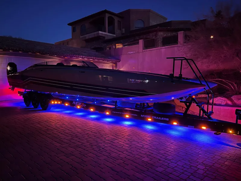 Slide: The Image of 2021 Daves Custom Boats M-37R on trailer with vibrant blue and red lighting. - 4