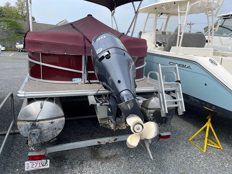 Slide: The Image of 2022 Starcraft LX20R pontoon boat with outboard motor, parked on a trailer. - 2