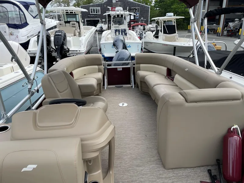 Slide: The Image of 2022 Starcraft LX20R pontoon boat with beige seating, docked among other boats. - 3