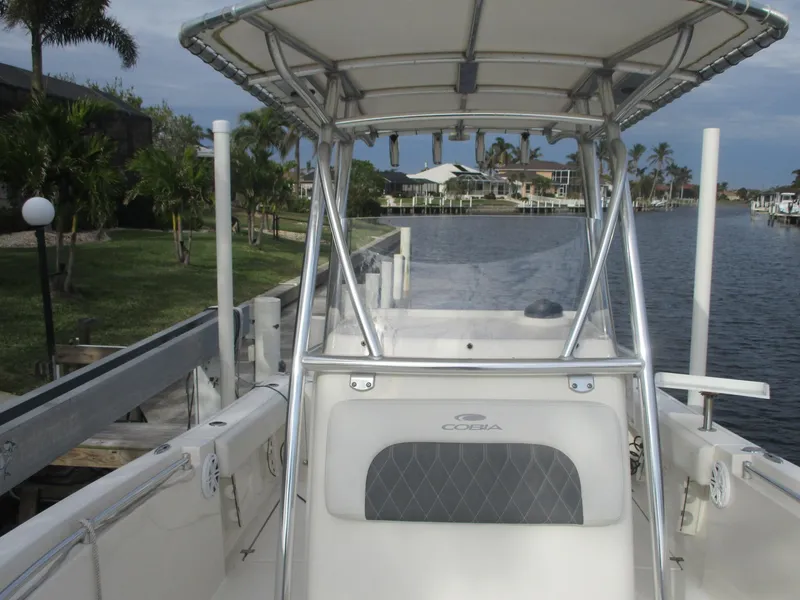 Slide: The Image of 2022 Cobia 237 Center Console boat docked by a canal with palm trees. - 25