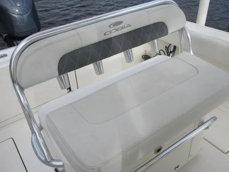 Slide: The Image of 2022 Cobia 237 Center Console boat seat with rod holders, on a calm water background. - 28
