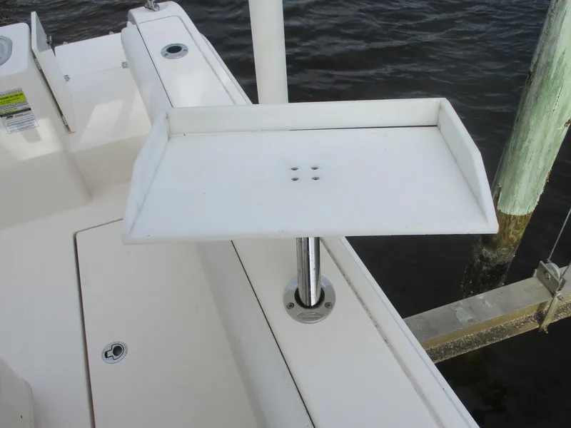 Slide: The Image of Cobia 237 Center Console 2022 boat with a white accessory tray near the water. - 31