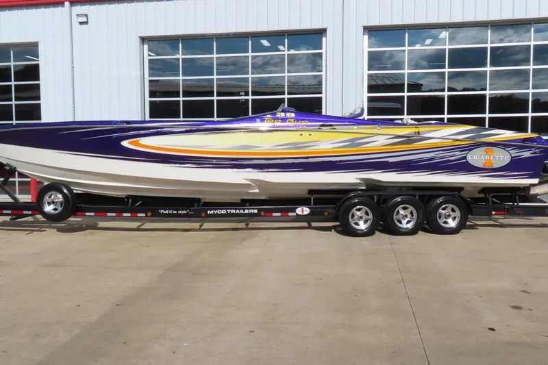 The Image of 2005 Cigarette 39 Top Gun speedboat on trailer, vibrant purple and yellow design. - 0