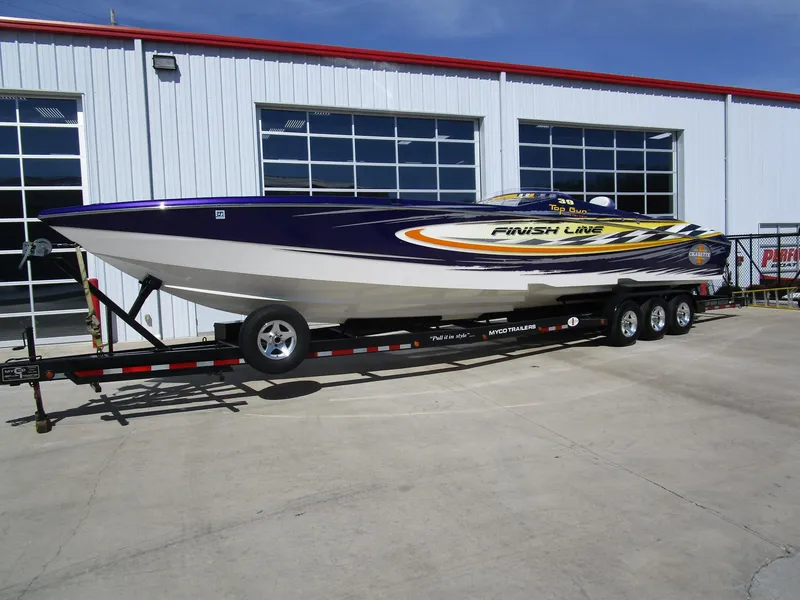 Slide: The Image of 2005 Cigarette 39 Top Gun speedboat on trailer, vibrant design, parked outdoors. - 2