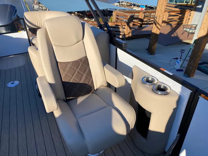 Slide: The Image of 2025 SunCatcher Elite 324 SS boat interior with beige seating and cup holders. - 19