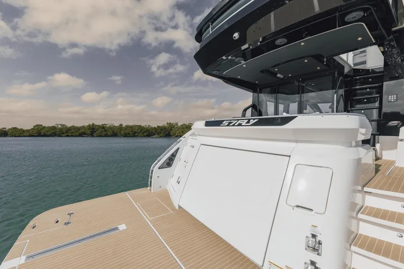Slide: The Image of 2025 Cruisers Yachts 57 Fly, luxury yacht docked on serene water, showcasing sleek design. - 14