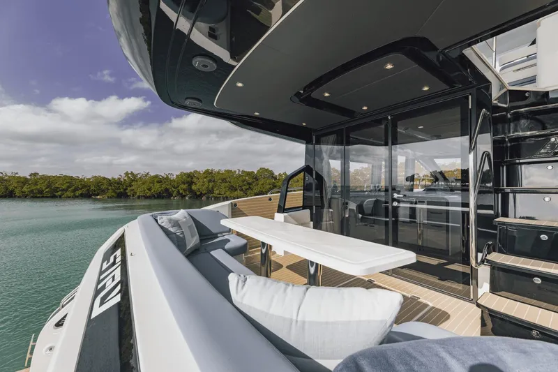 Slide: The Image of Luxurious 2025 Cruisers Yachts 57 Fly deck with seating, overlooking serene water and lush greenery. - 17