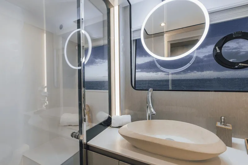 Slide: The Image of Luxurious bathroom in 2025 Cruisers Yachts 57 Fly, featuring modern sink and illuminated mirrors. - 50