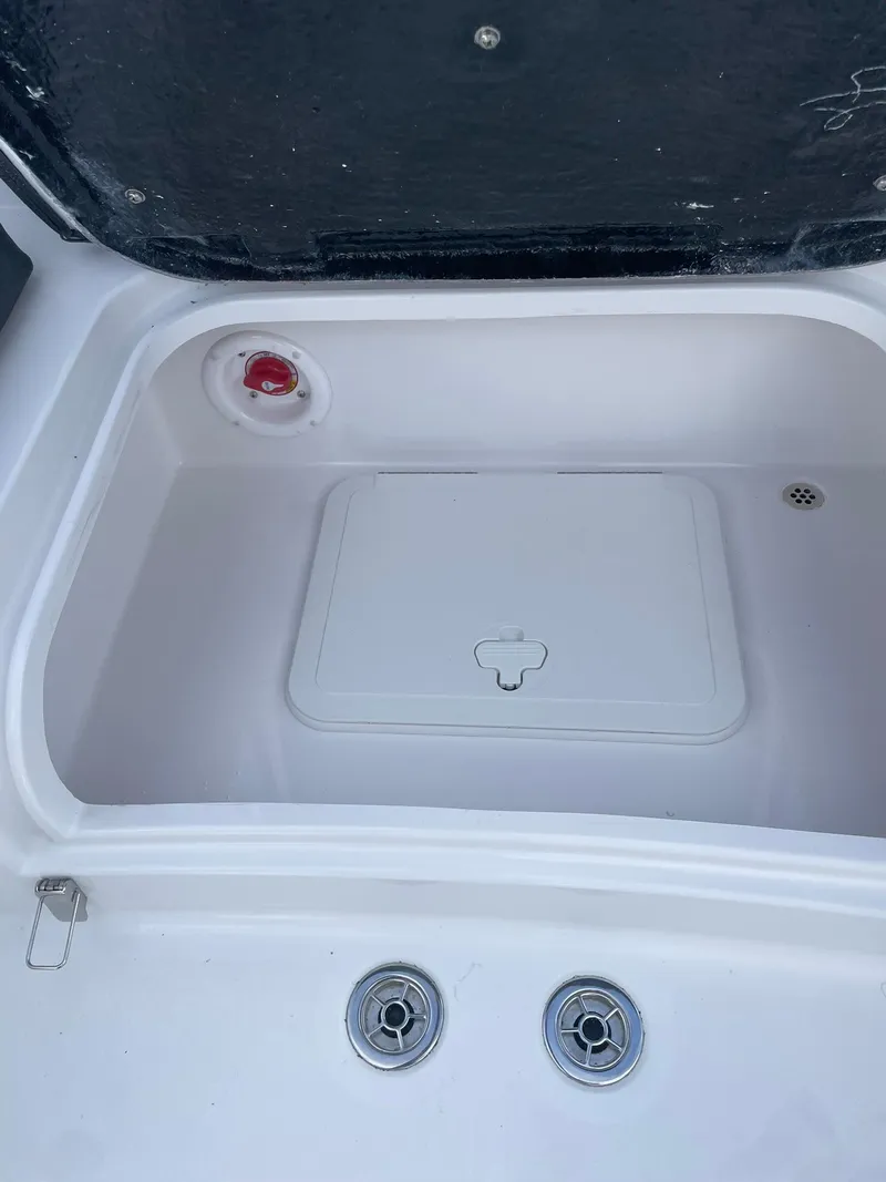 Slide: The Image of 2025 Stingray 23 OSX boat storage compartment with lid and drainage features. - 13