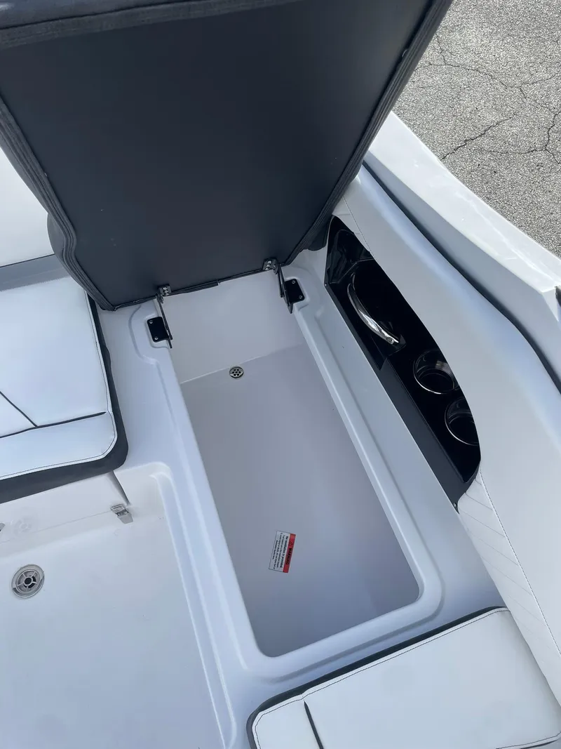 Slide: The Image of 2025 Stingray 23 OSX boat storage compartment with open lid, showcasing interior space. - 14