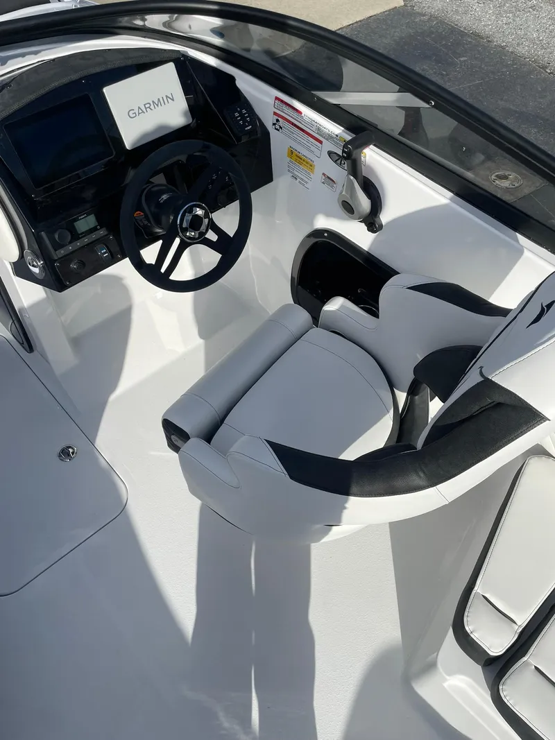 Slide: The Image of 2025 Stingray 23 OSX boat cockpit with Garmin navigation system and sleek white seating. - 16