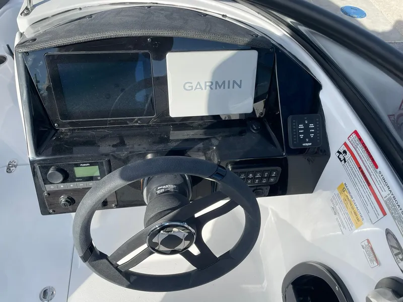 Slide: The Image of 2025 Stingray 23 OSX boat dashboard with Garmin navigation system and steering wheel. - 18