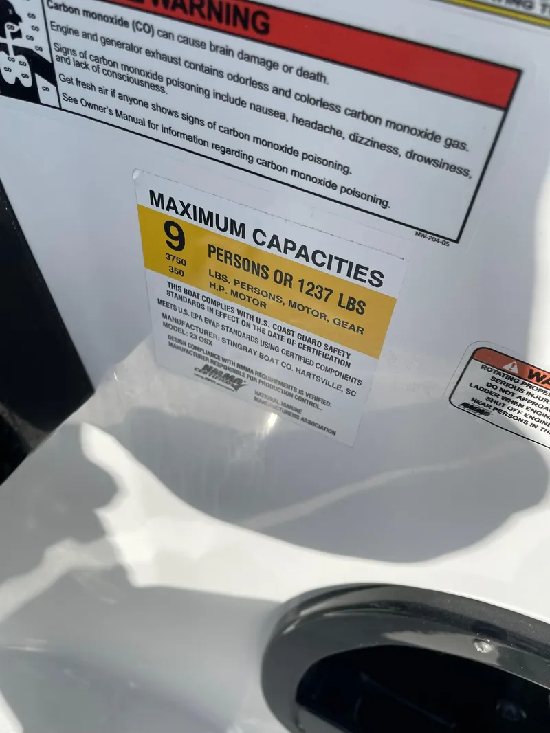 Slide: The Image of Warning label on 2025 Stingray 23 OSX showing maximum capacity of 9 persons or 1237 lbs. - 20