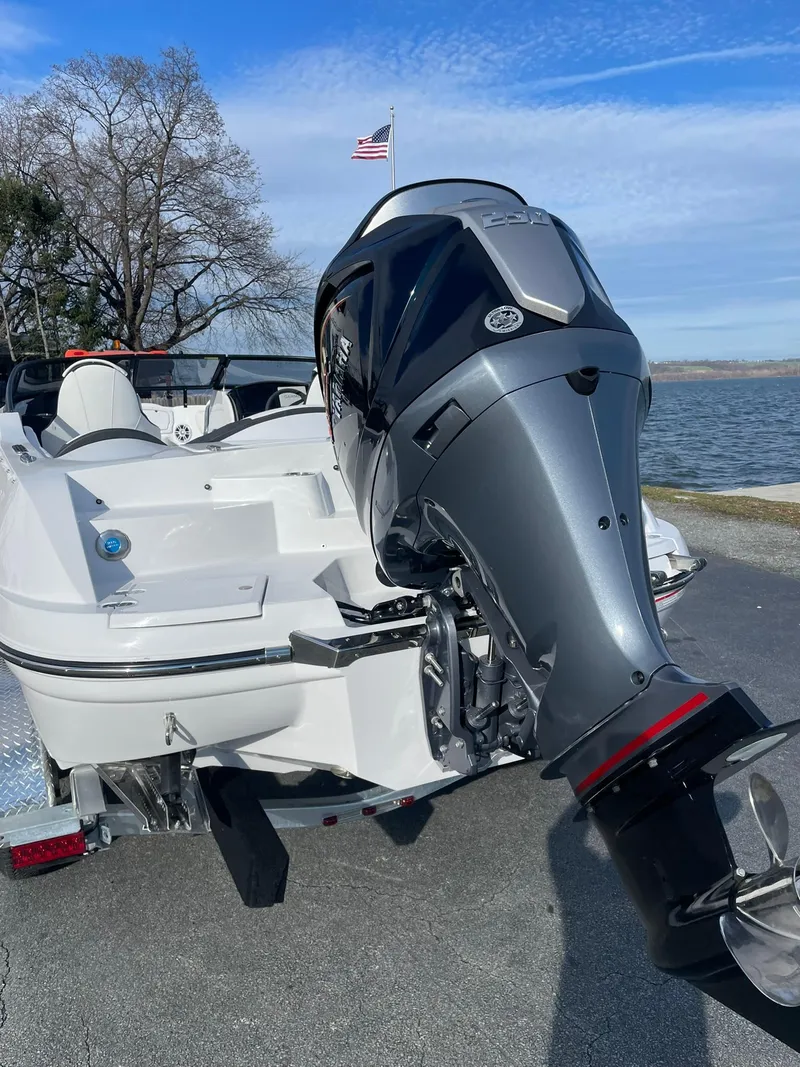 Slide: The Image of 2025 Stingray 23 OSX boat with powerful outboard motor by a lakeside. - 3