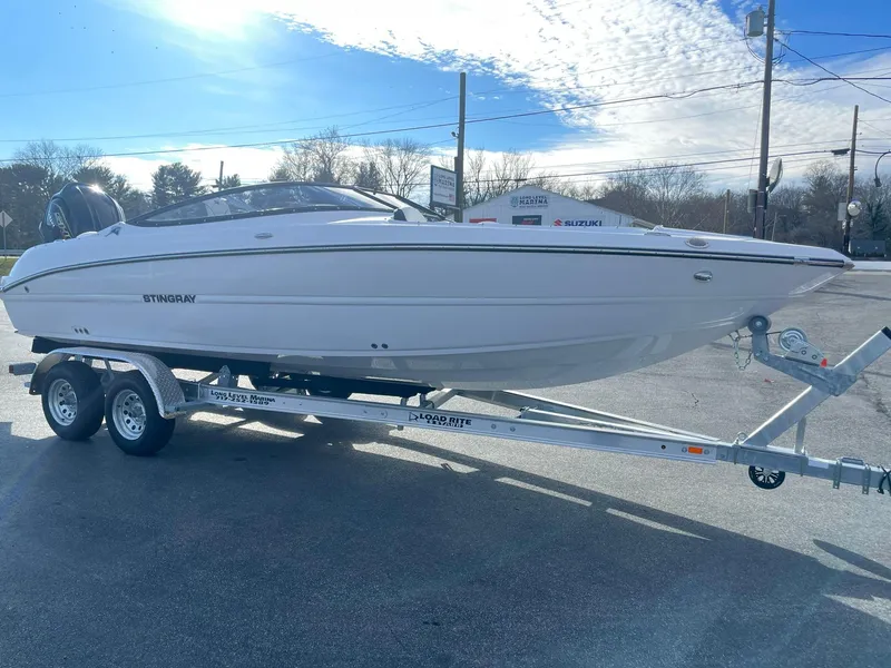 Slide: The Image of 2025 Stingray 23 OSX boat on a trailer under a clear blue sky. - 6