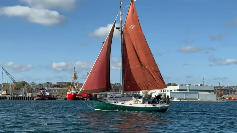 The Image of Sailboat Legnos Mystic 30 (1978) with red sails on a sunny day near a harbor. - 1