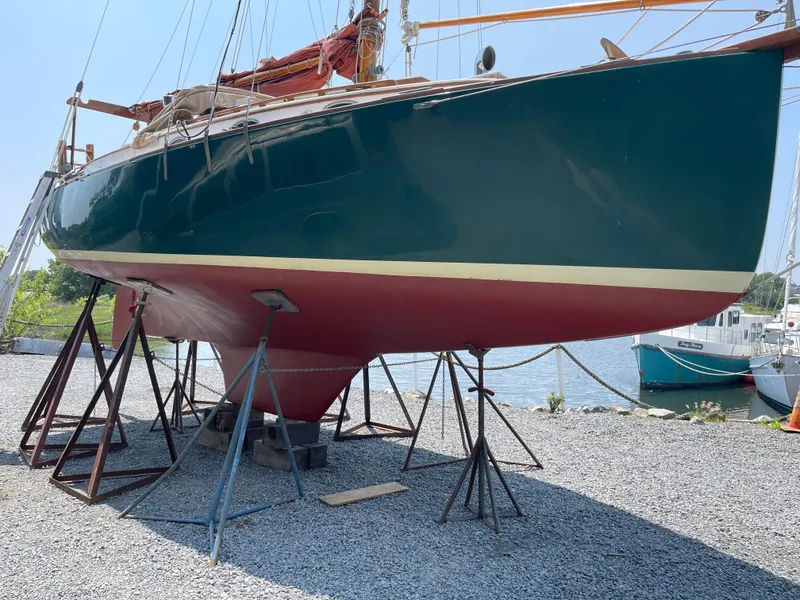 Slide: The Image of 1978 Legnos Mystic 30 sailboat on stands, green hull, red bottom, outdoor display. - 11