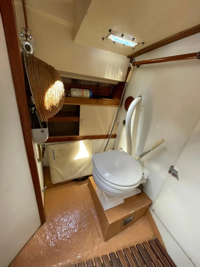 Slide: The Image of 1978 Legnos Mystic 30 boat bathroom with toilet, storage shelves, and wooden accents. - 3