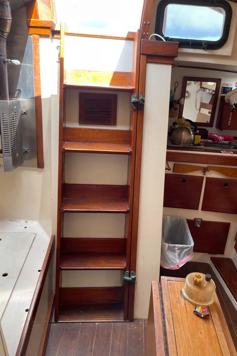 Slide: The Image of Interior of 1978 Legnos Mystic 30 sailboat with wooden steps and nautical decor. - 7