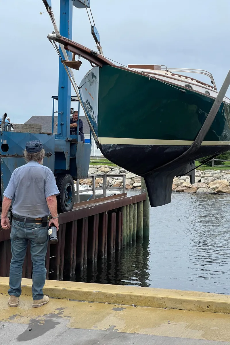 Slide: The Image of A 1978 Legnos Mystic 30 sailboat being lifted by a crane near the water. - 8