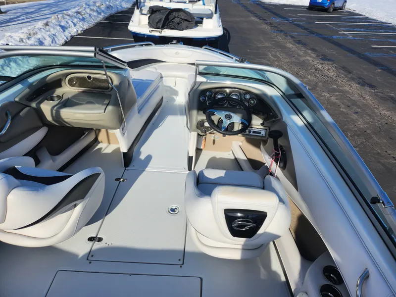Slide: The Image of 2012 Crownline 21 SS boat interior with white seating and dashboard, parked on snowy pavement. - 11