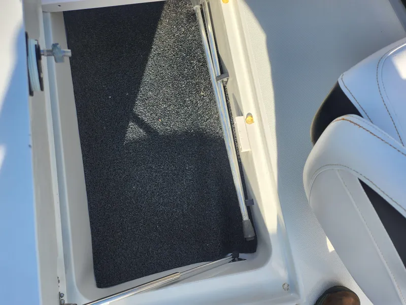 Slide: The Image of Storage compartment in a 2012 Crownline 21 SS boat, featuring black carpet and white seating. - 13