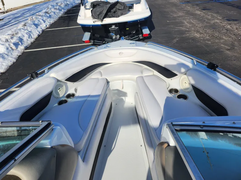 Slide: The Image of 2012 Crownline 21 SS boat interior with white seating and cup holders, parked on snowy pavement. - 15