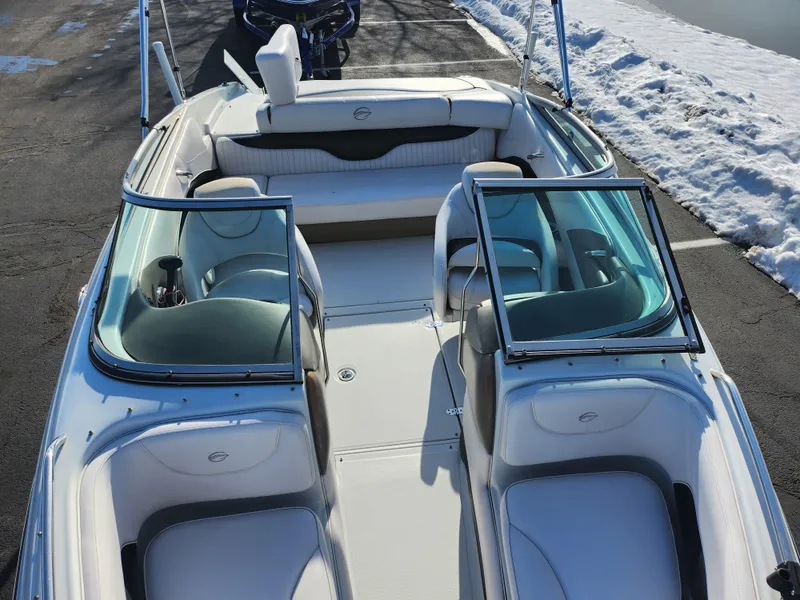 Slide: The Image of 2012 Crownline 21 SS boat interior with white seating and open windshield, parked on snowy pavement. - 18