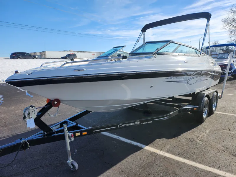 Slide: The Image of 2012 Crownline 21 SS boat on trailer, parked outdoors under clear blue sky. - 5