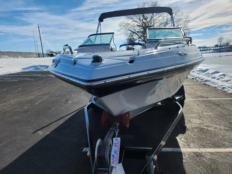 Slide: The Image of 2012 Crownline 21 SS boat on trailer, parked on snowy pavement under clear sky. - 6