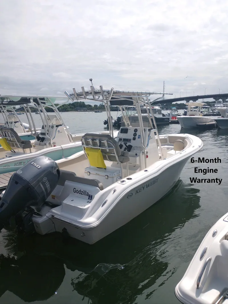 Slide: The Image of 2022 Key West 219 FS boat docked, featuring a 6-month engine warranty. - 0