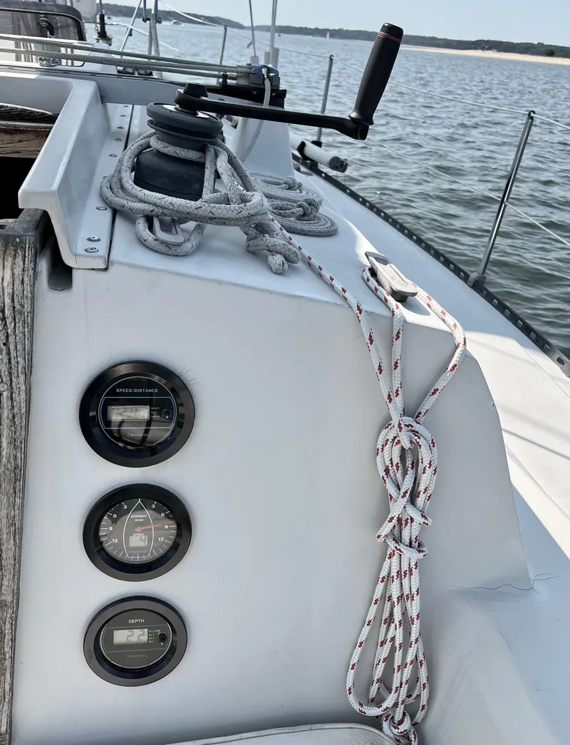 Slide: The Image of 1983 C&C 35 MKIII sailboat deck with winch, ropes, and gauges by the water. - 11