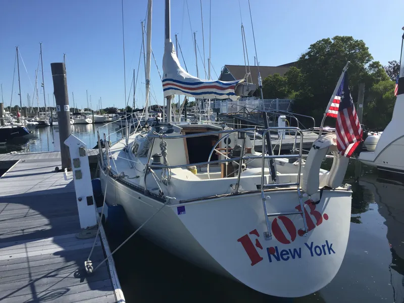 Slide: The Image of 1983 C&C 35 MKIII sailboat docked in a marina, displaying American flag. - 2