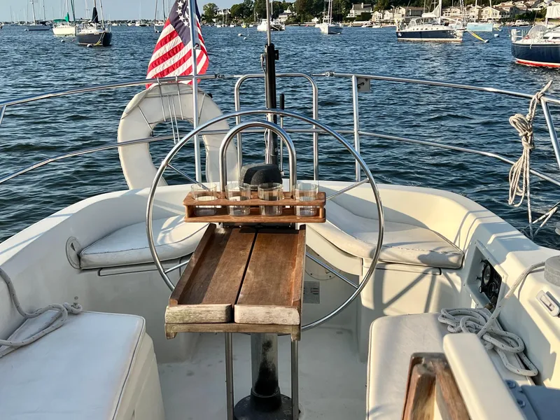 Slide: The Image of 1983 C&C 35 MKIII sailboat cockpit with wooden table, steering wheel, and American flag. - 20