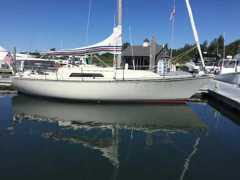 Slide: The Image of 1983 C&C 35 MKIII sailboat docked in a marina, reflecting on calm water. - 3