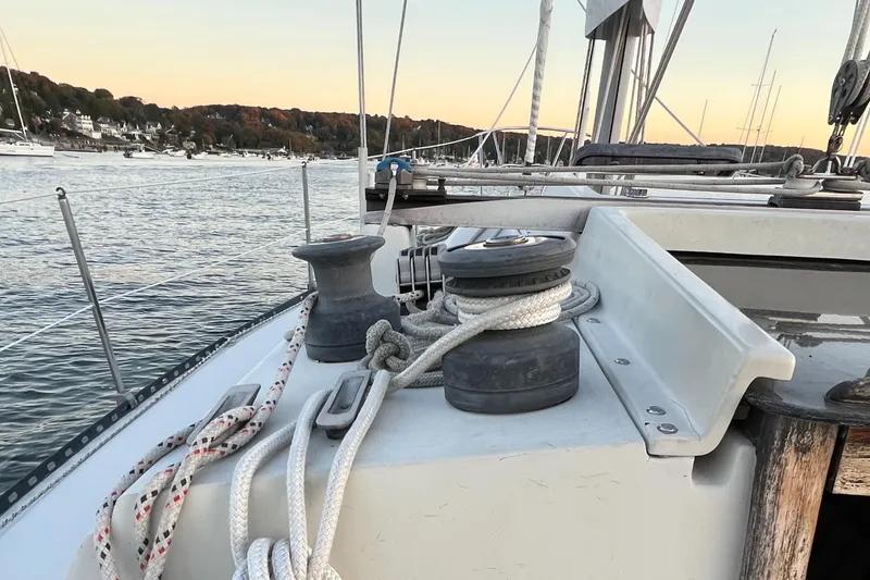 Slide: The Image of 1983 C&C 35 MKIII sailboat deck with winches and ropes, docked by a scenic shoreline. - 32