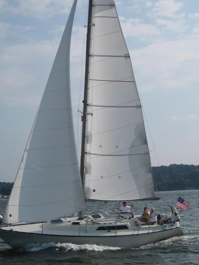 Slide: The Image of 1983 C&C 35 MKIII sailboat on water, sails up, American flag, clear sky. - 5