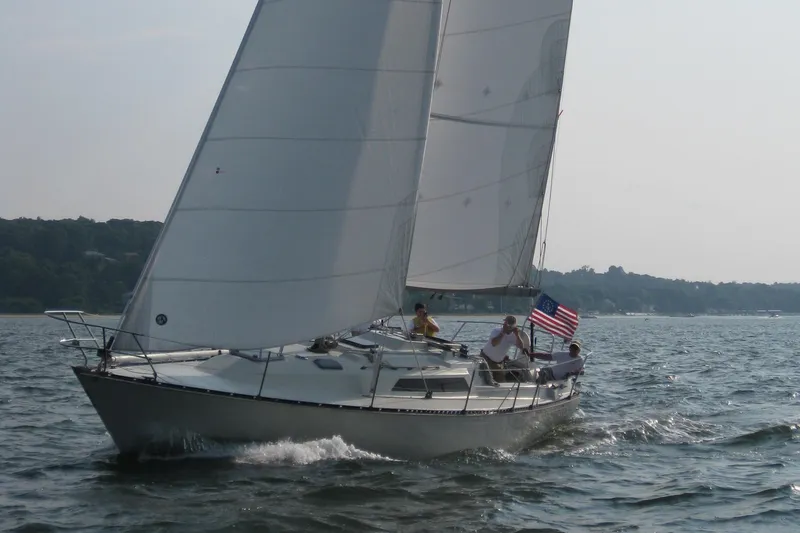 Slide: The Image of 1983 C&C 35 MKIII sailboat with American flag sailing on a calm lake. - 6