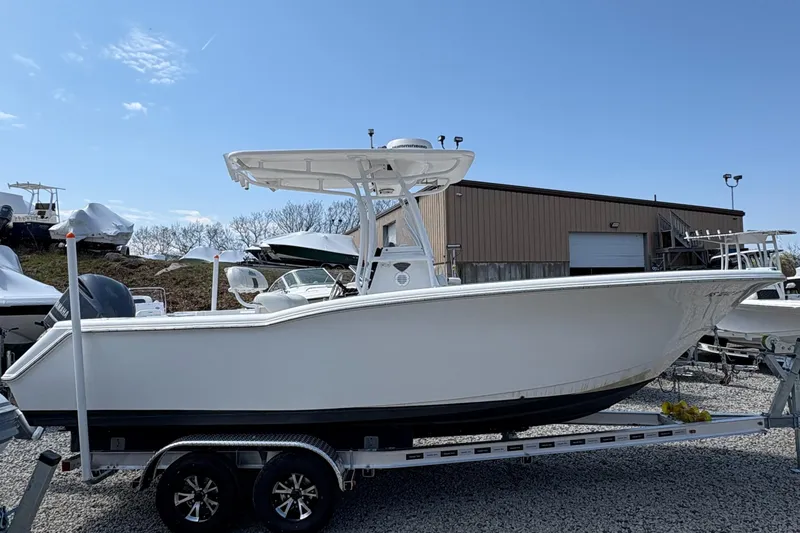 The Image of Tidewater 230 boat, 2013 model, on a trailer in a boatyard under clear blue sky. - 0