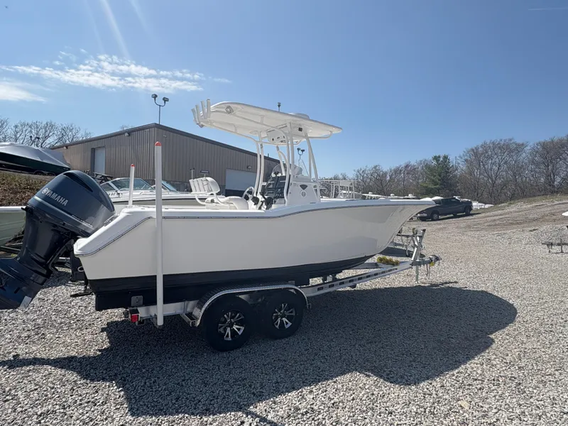 Slide: The Image of 2013 Tidewater 230 boat on trailer, parked outdoors under clear blue sky. - 2