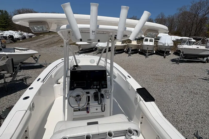 Slide: The Image of 2013 Tidewater 230 boat with center console and rod holders, parked on gravel lot. - 23