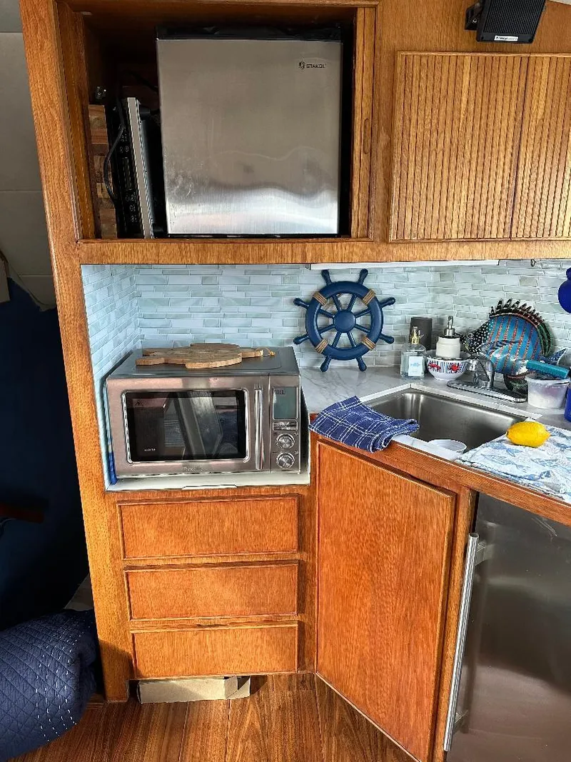 Slide: The Image of 1989 Bertram 43 Convertible kitchen with microwave, mini-fridge, and nautical decor. - 13