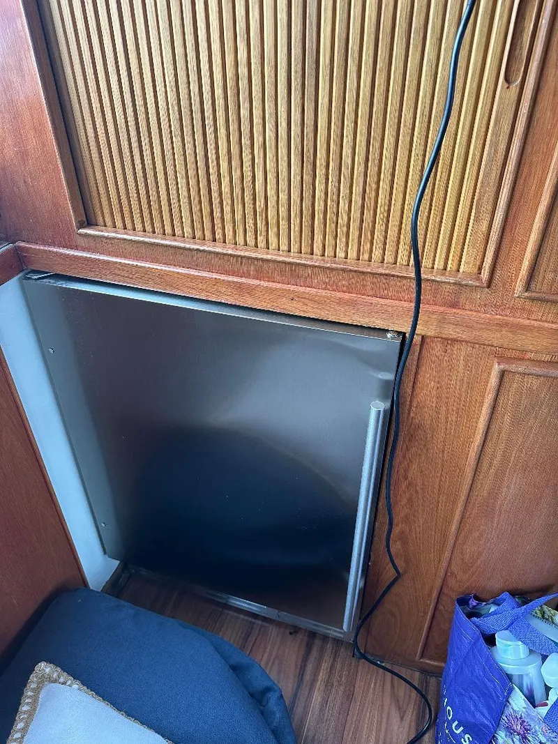 Slide: The Image of 1989 Bertram 43 Convertible interior with wooden paneling and a small refrigerator. - 18