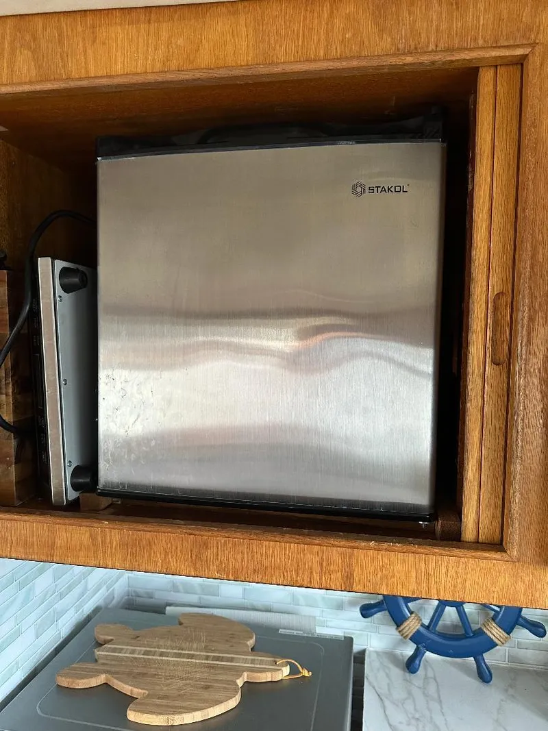 Slide: The Image of Stainless steel appliance in a wooden cabinet on a 1989 Bertram 43 Convertible boat. - 19