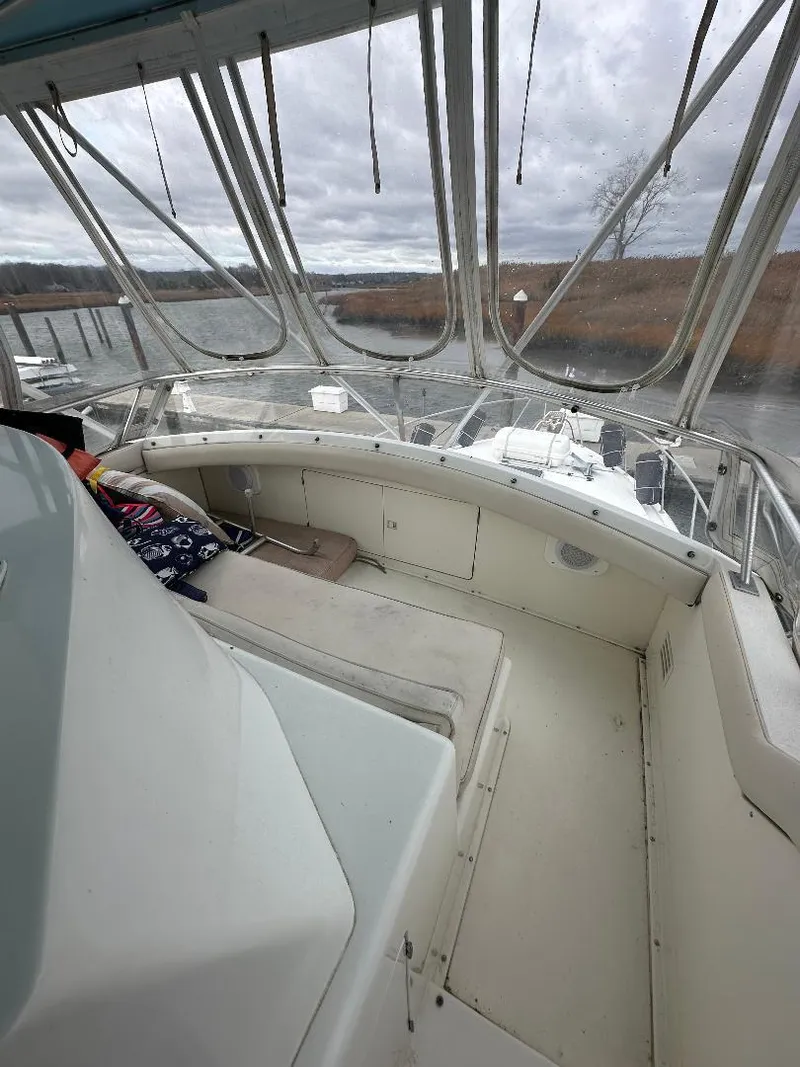 Slide: The Image of 1989 Bertram 43 Convertible boat interior with seating, enclosed by clear panels, on a cloudy day. - 24