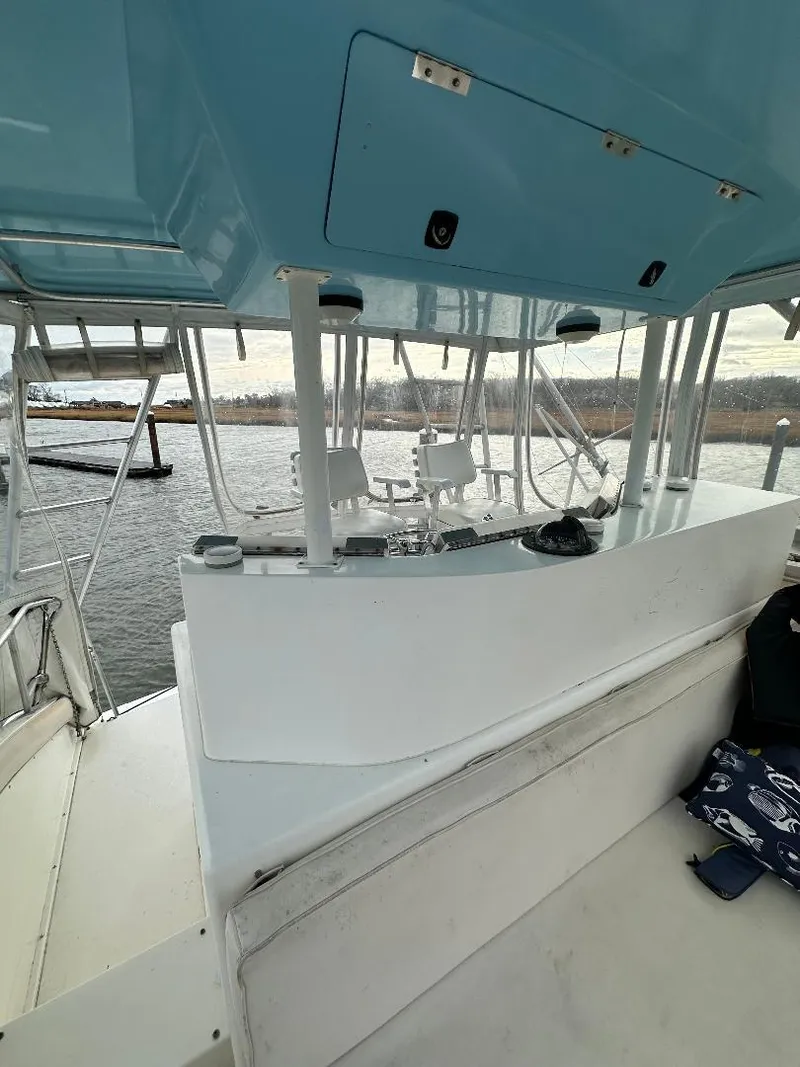 Slide: The Image of 1989 Bertram 43 Convertible yacht interior with blue ceiling and white seating, docked by the water. - 25